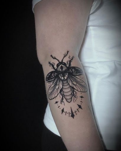 a black and white photo of a bee on someone's arm with an all seeing eye tattoo