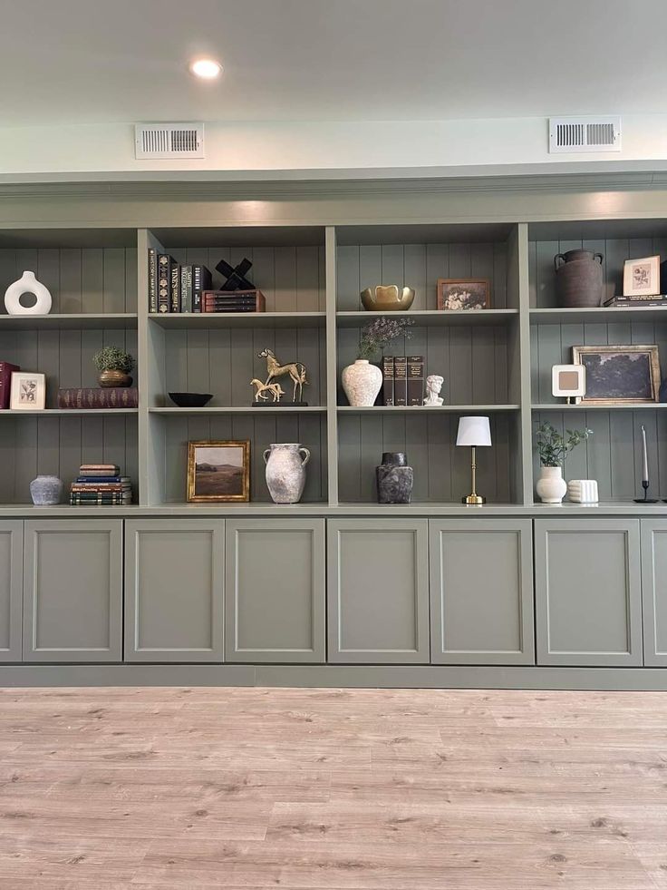 an empty living room with gray bookcases and wood flooring on the walls