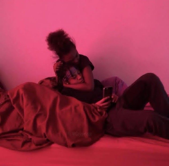 a woman laying on top of a bed next to a man holding a cell phone