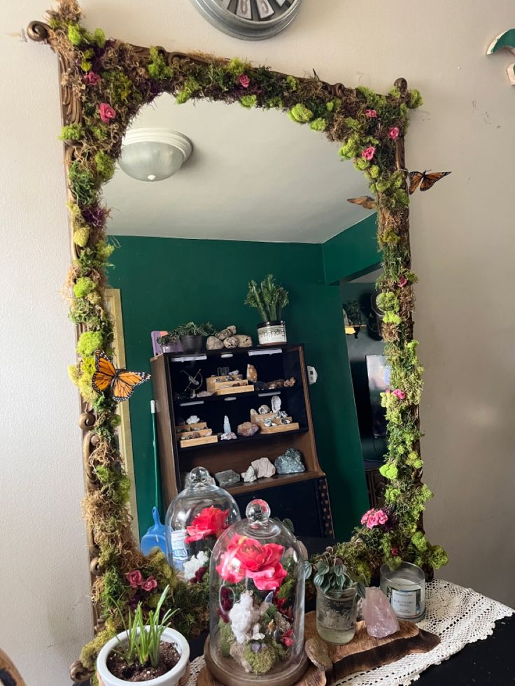 a mirror that has some plants in it and a clock on the wall behind it