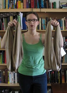 a woman standing in front of a bookshelf holding up two jacket jackets over her shoulders