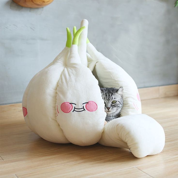 a cat hiding in a stuffed animal that is shaped like an egg with glasses on it