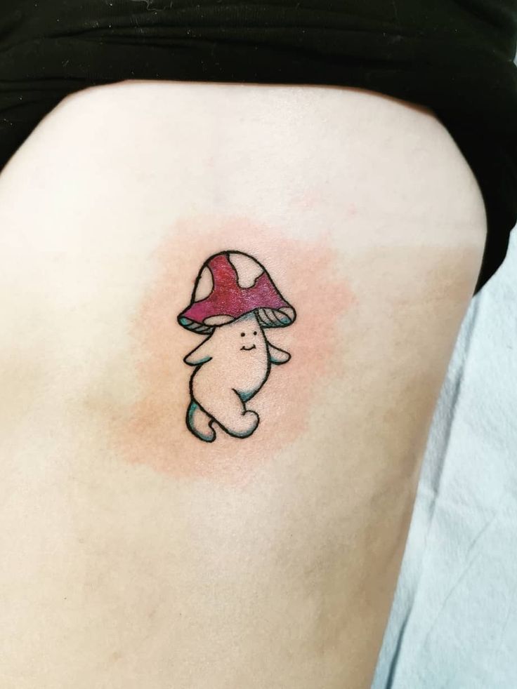 a small mushroom tattoo on the back of a woman's stomach