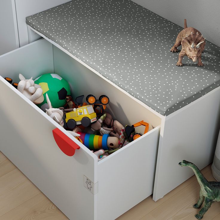 a toy box with toys in it and a cat on the floor