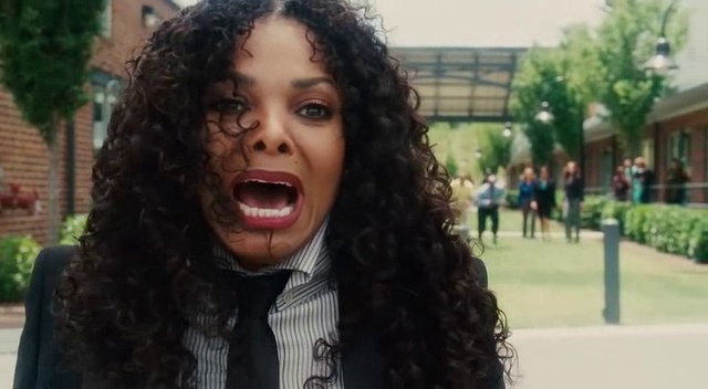 a woman with long curly hair wearing a suit and tie in front of a building