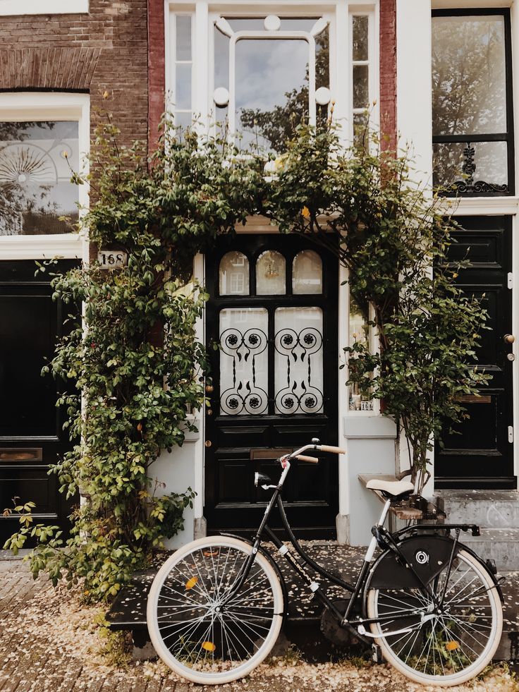 a bicycle parked in front of a building with ivy growing on it's door