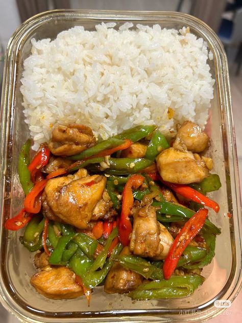 a plastic container filled with rice and chicken next to green beans, red peppers and broccoli