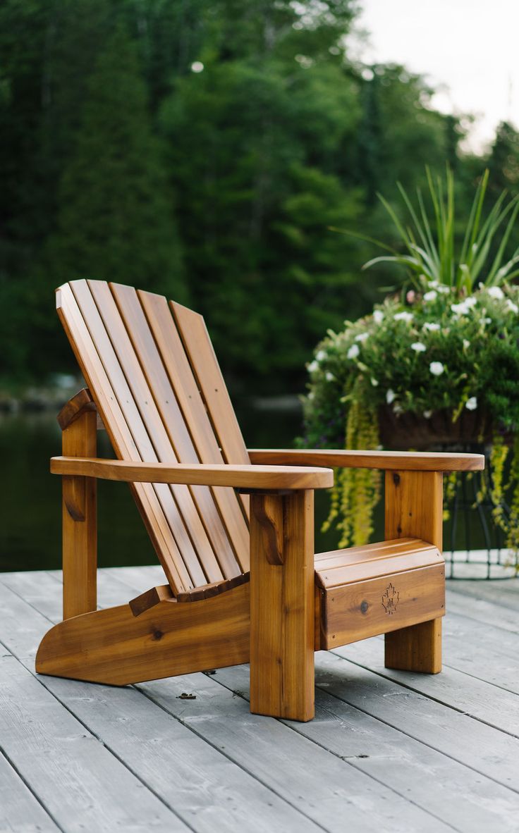 a wooden chair sitting on top of a wooden deck next to a potted plant