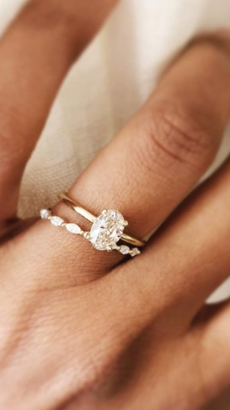 a woman's hand with a diamond ring on her finger and an engagement band