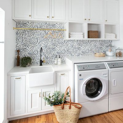 a washer and dryer in a white laundry room with wood flooring, cabinets and drawers