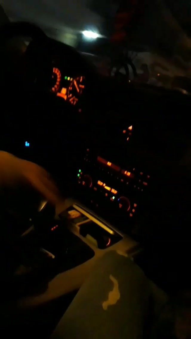 a person driving in the dark at night with their hands on the steering wheel and dashboard