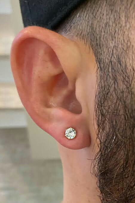 a man wearing a baseball cap and earring with a small diamond in the middle