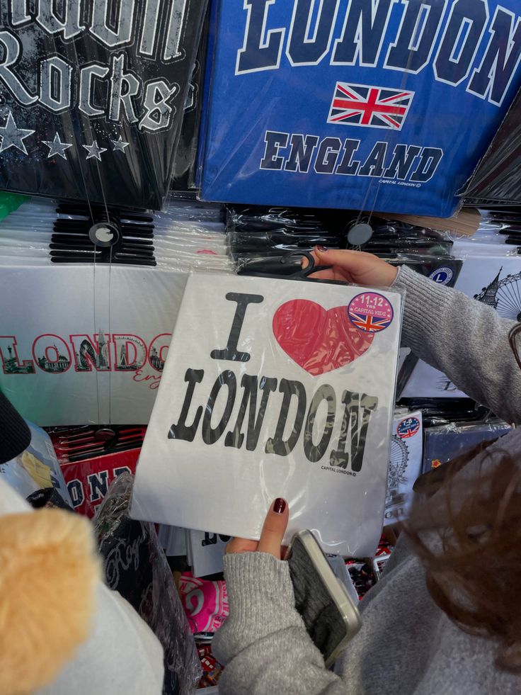 a person holding up a sign that says i love london in front of other signs