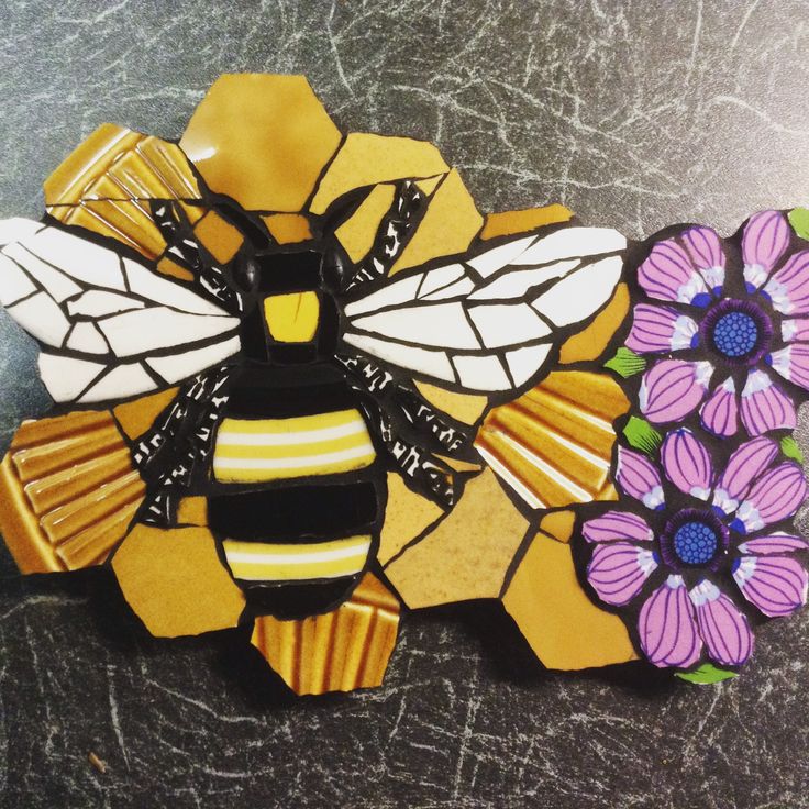 a stained glass bee sitting on top of a yellow and purple flowered tile piece