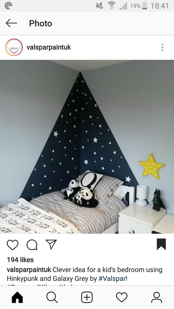 a bed room with a neatly made bed next to a night stand and a star decoration on the wall