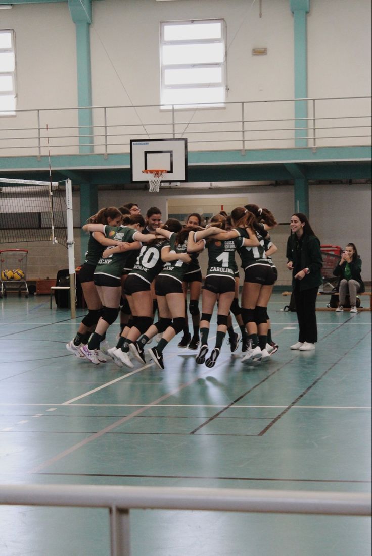 a group of young women standing next to each other on top of a basketball court