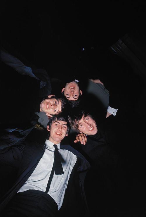 four men in suits and ties posing for a photo together at night with their arms around each other