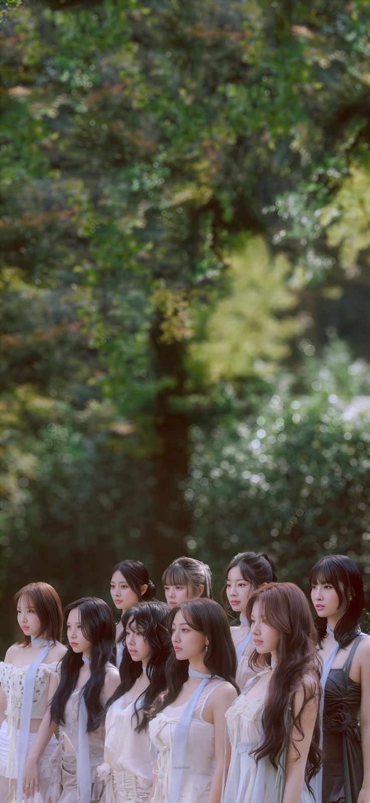 a group of young women standing next to each other in front of some green trees