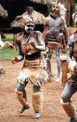 an image of some people that are dancing in the dirt with feathers on their head