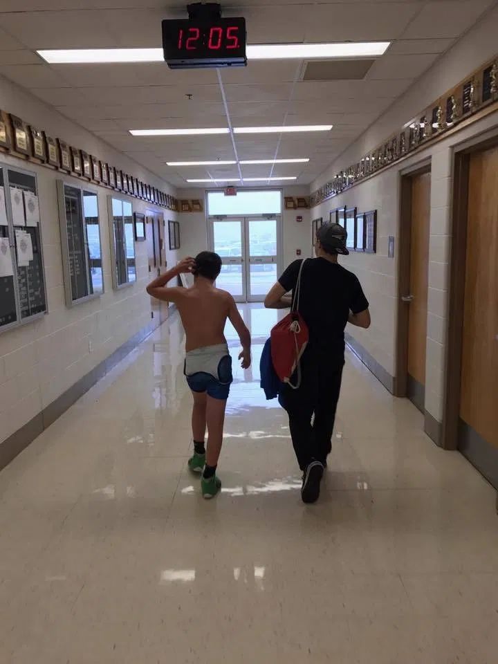 two people walking down a hallway with no shirts on