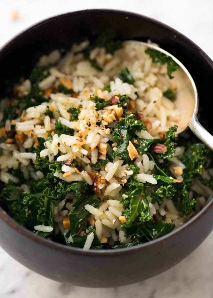 a bowl filled with rice, greens and nuts