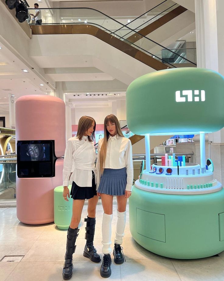 two young women standing next to each other in front of a display case at a mall