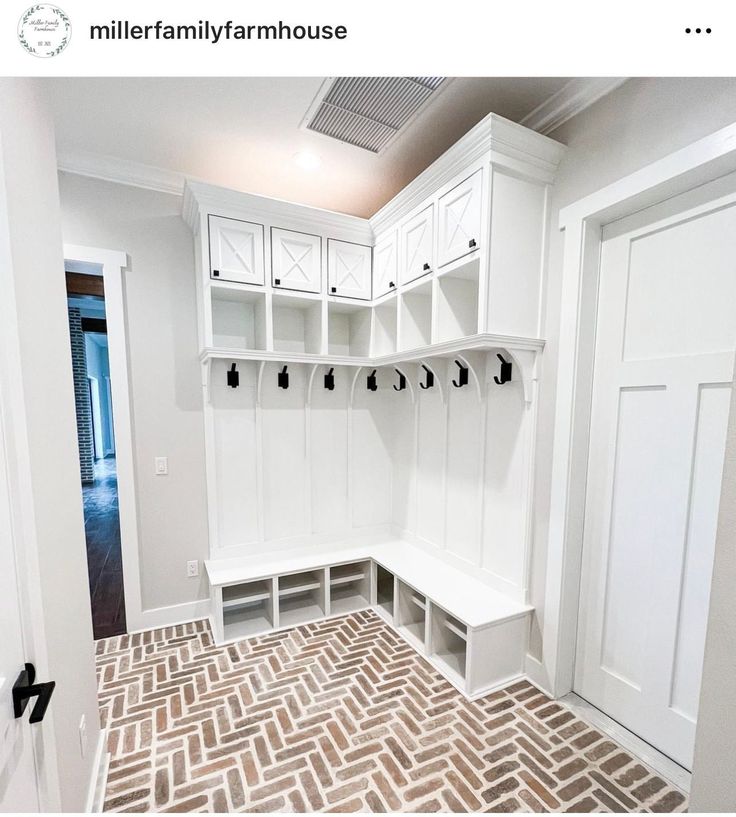 a mud room with white cabinets and benches