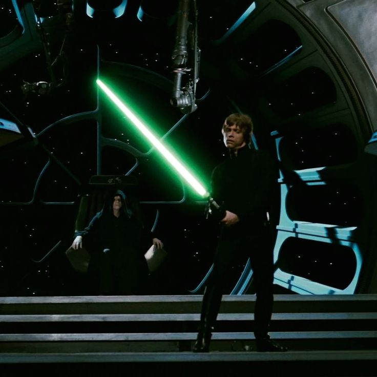 two men standing next to each other in front of a clock with lights on it