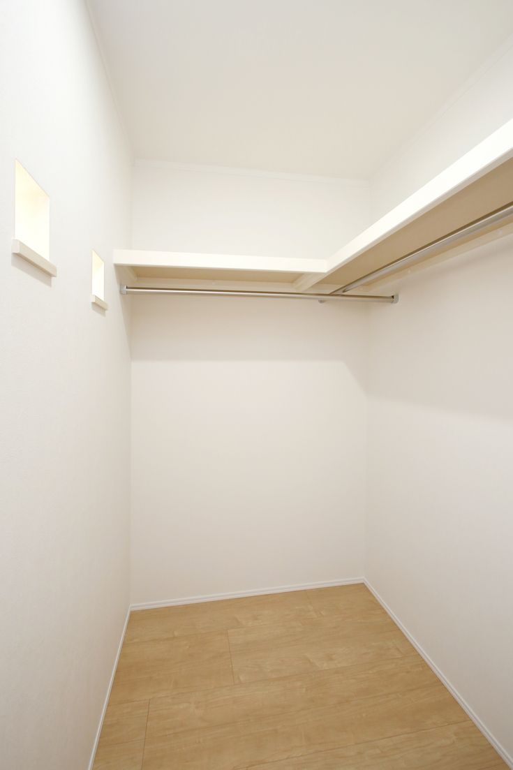 an empty closet with white walls and wooden floors