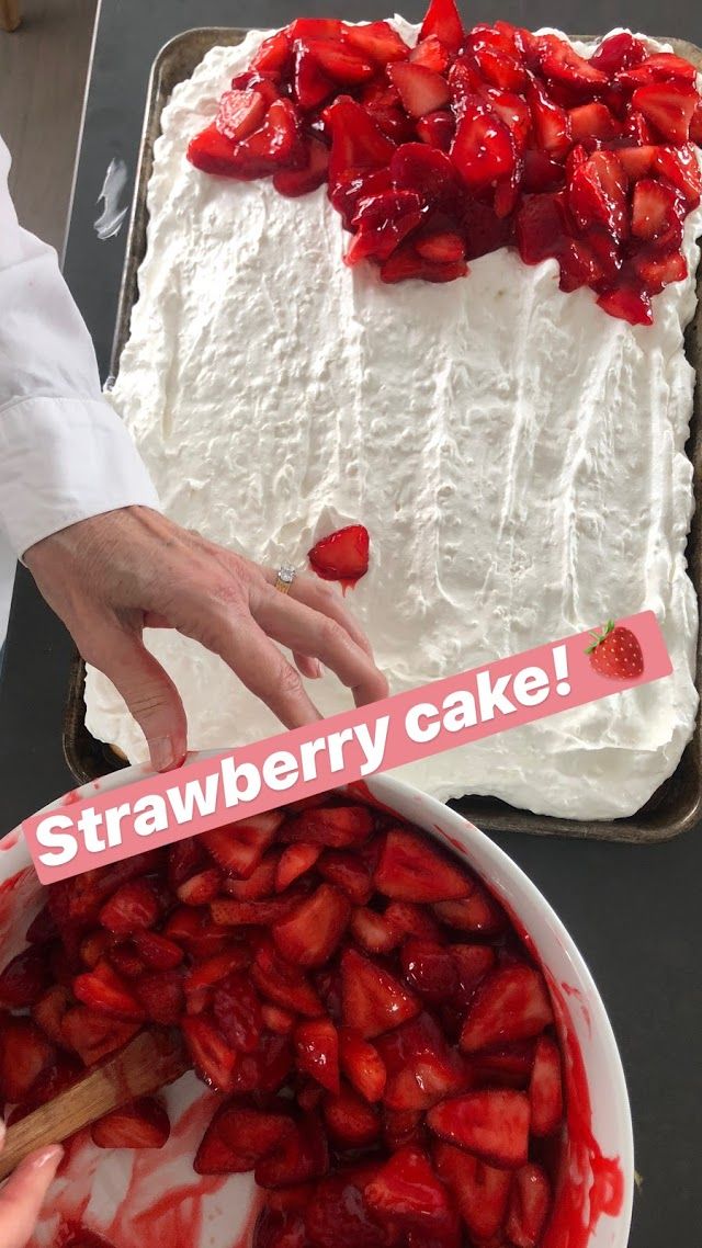 someone is decorating a strawberry cake with white frosting and strawberries on top