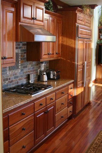 a kitchen with wooden cabinets and granite counter tops, along with hardwood flooring that matches the walls