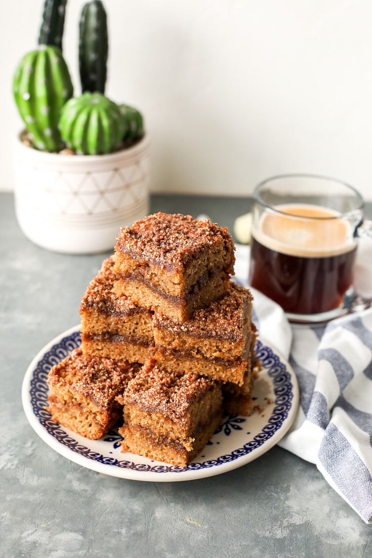 stack of cinnamon sugar bars sitting on a plate next to a cup of coffee and cacti