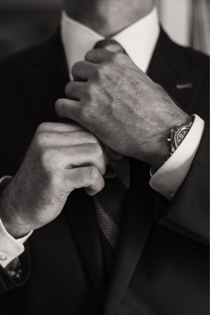 a close up of a person wearing a suit and tie with his hands on his lapel