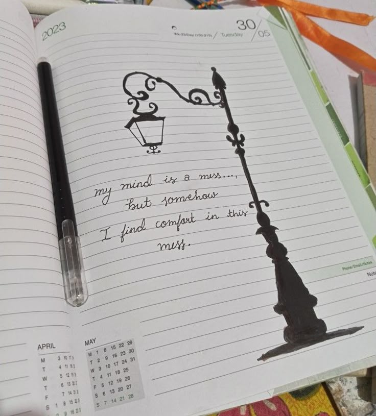 an open notebook with a drawing of a lamp post on it and a date book next to it