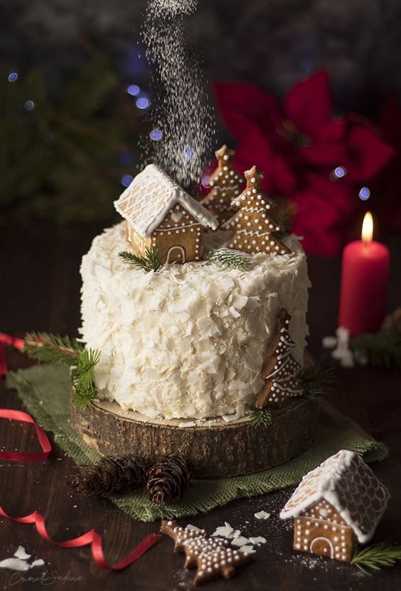 a cake with white frosting and christmas decorations on it, sitting next to a lit candle