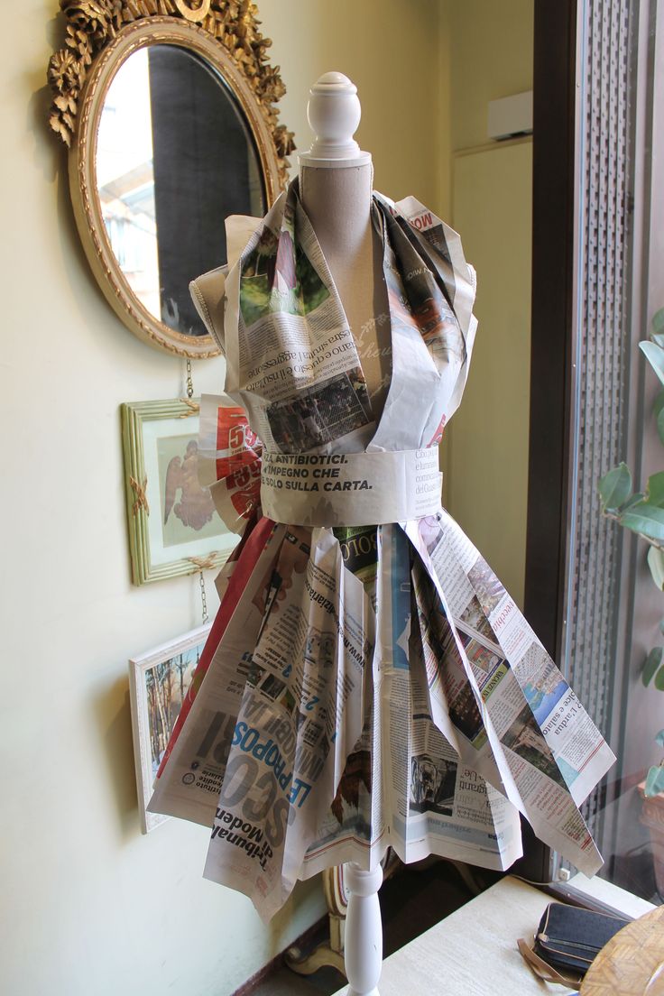 a dress made out of newspapers sitting on top of a table next to a mirror