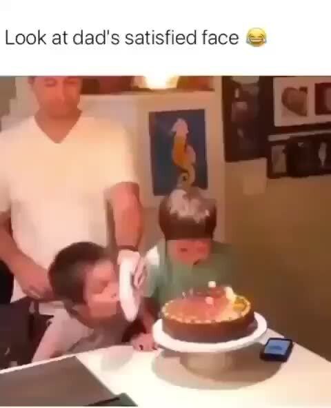 a young boy blowing out the candles on his birthday cake while an older man watches