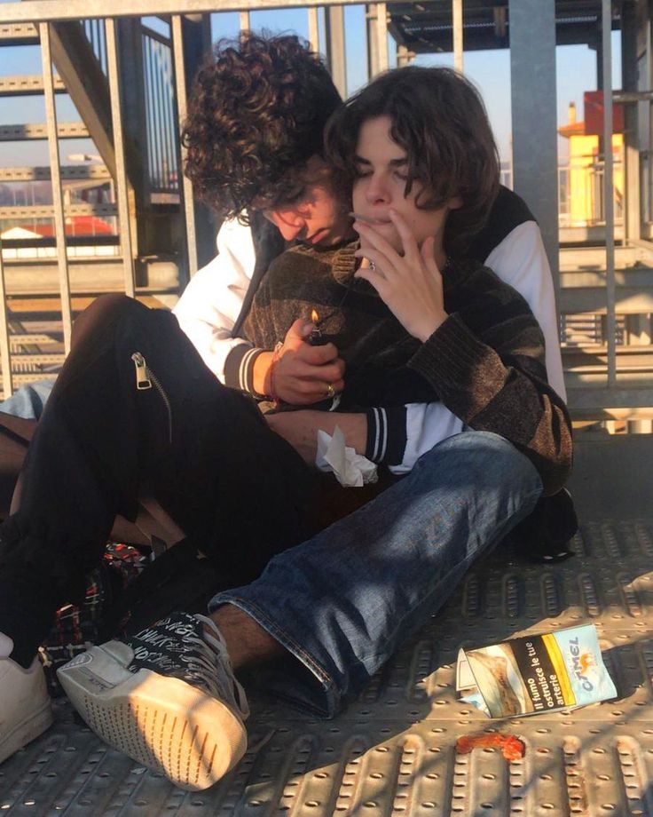 two young men sitting on the ground next to each other