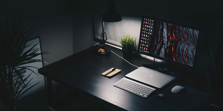 a desk with a laptop, keyboard and mouse on it in front of a computer monitor