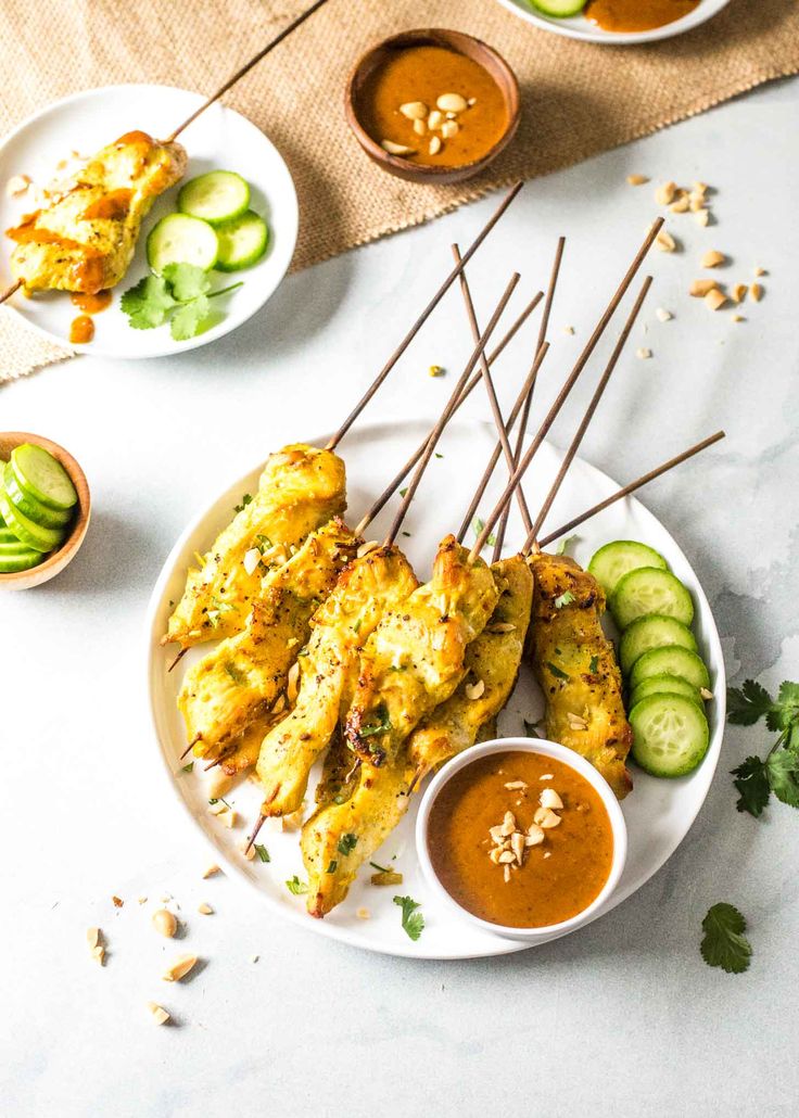 chicken satay served with dipping sauce and cucumbers