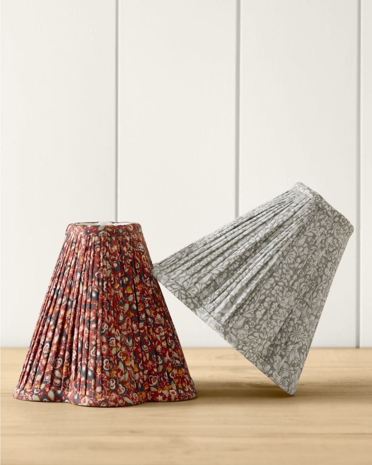 two small lampshades sitting on top of a wooden table next to each other