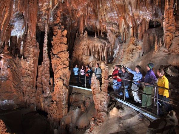 several people are standing in the cave looking at their cell phones and taking pictures with them