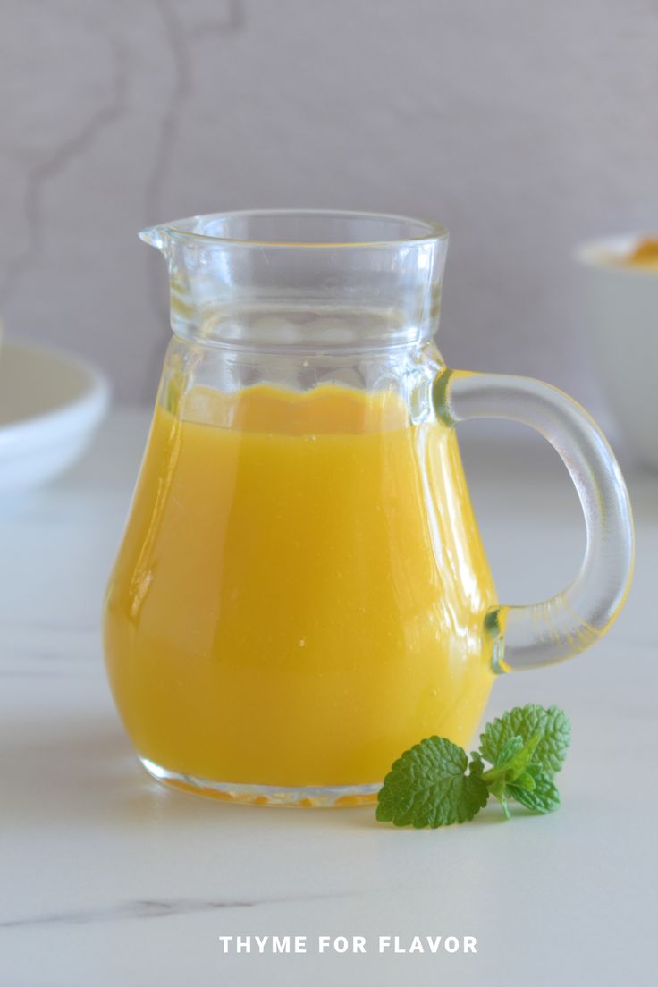 a glass pitcher filled with orange juice on top of a table