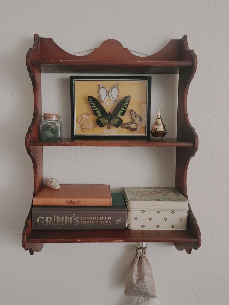 some books are sitting on a shelf in front of a wall with a framed butterfly