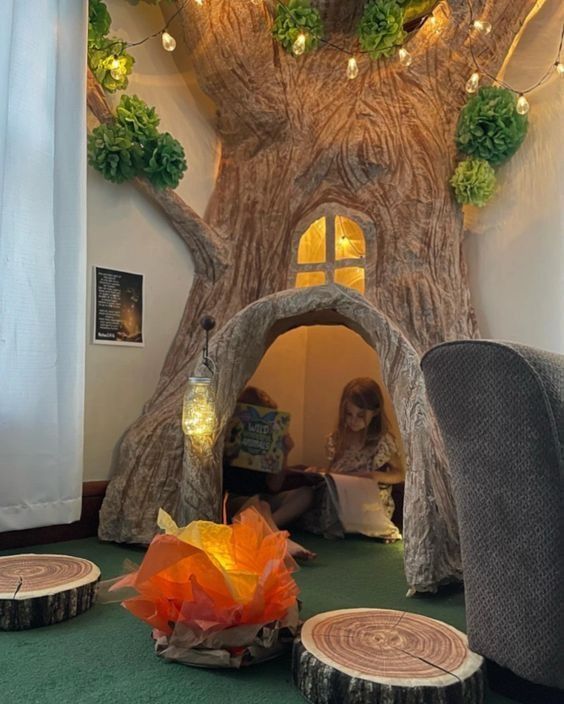 there is a tree house in the middle of the room with lights on it and two people reading