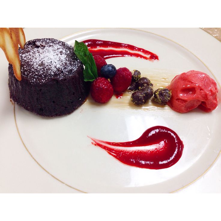 a white plate topped with a piece of chocolate cake and berries on top of it