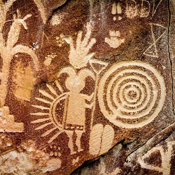 rock art depicting people and animals on the side of a mountain