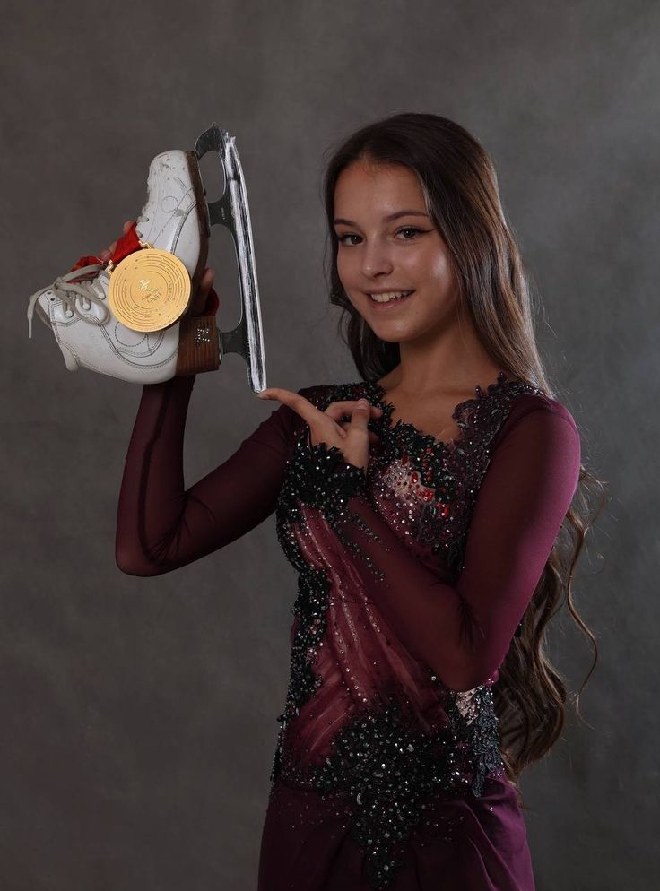 a woman holding up a pair of tennis shoes and a gold medal in her hand