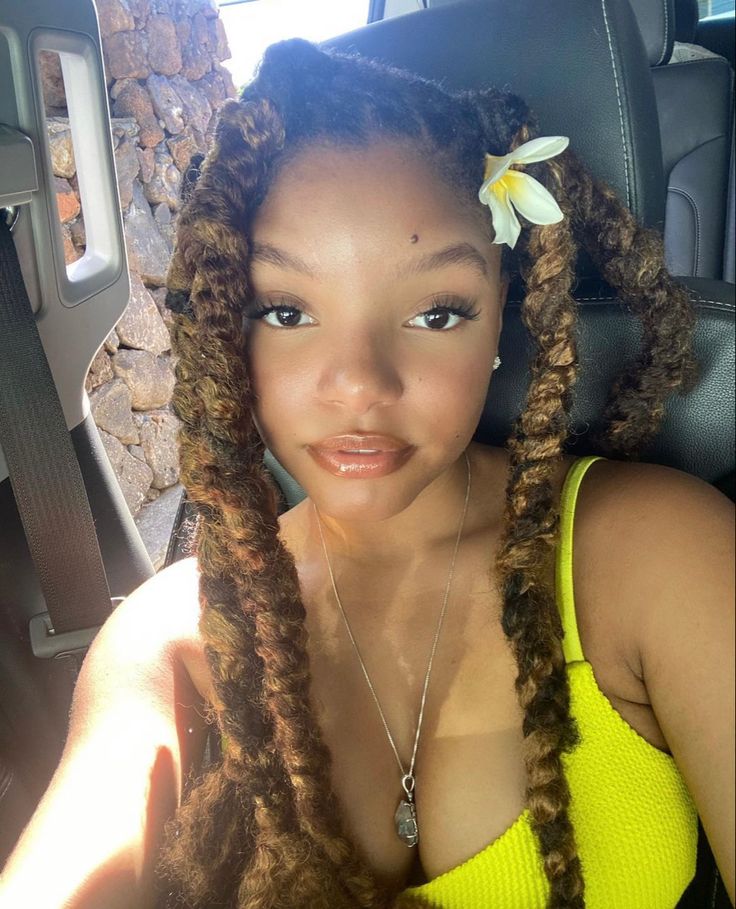 a woman sitting in the back seat of a car with long dreadlocks on her head