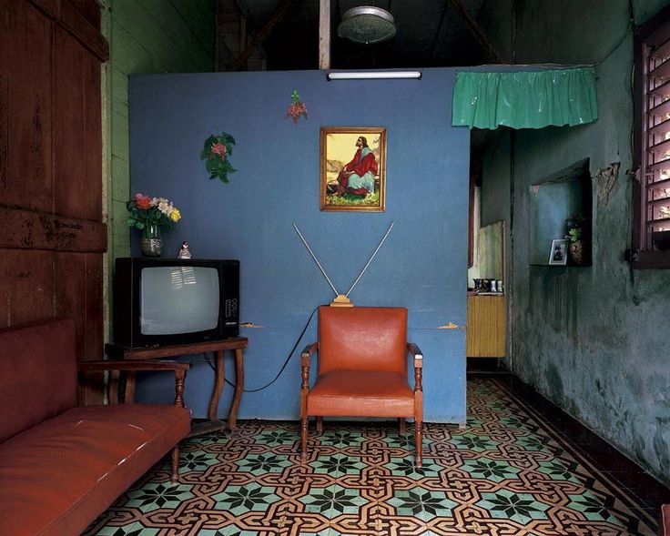 a living room with a couch, chair and television set in front of a painting on the wall